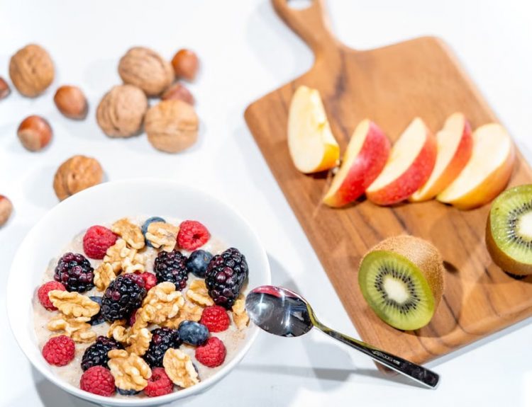 A nutritious breakfast bowl featuring fresh berries and walnuts, served with sliced fruit and kiwi.